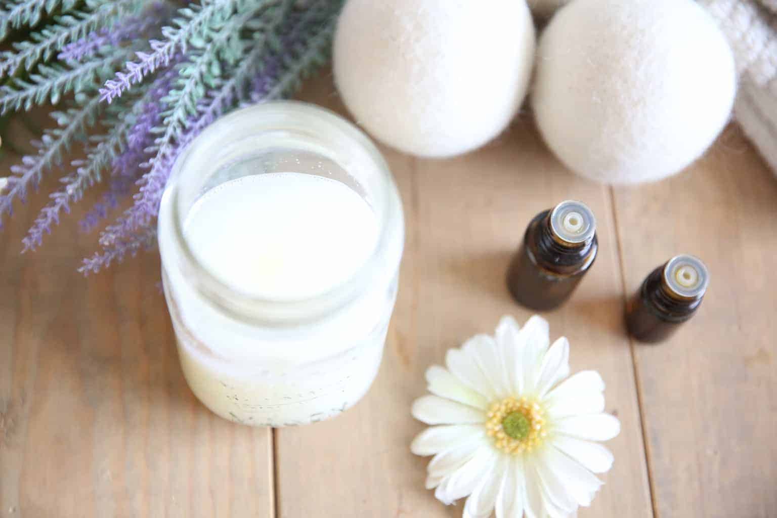 Homemade laundry soap in mason jar with dryer balls on wooden table.