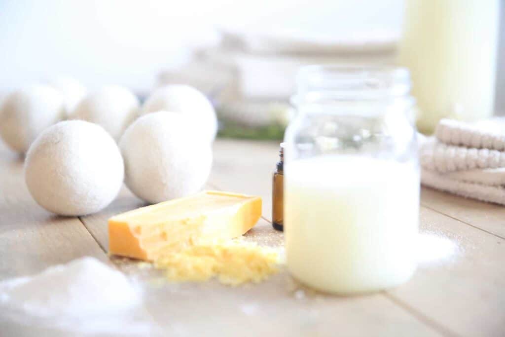 Natural dryer balls with natural laundry detergent and a shredded soap bar on the tabletop.