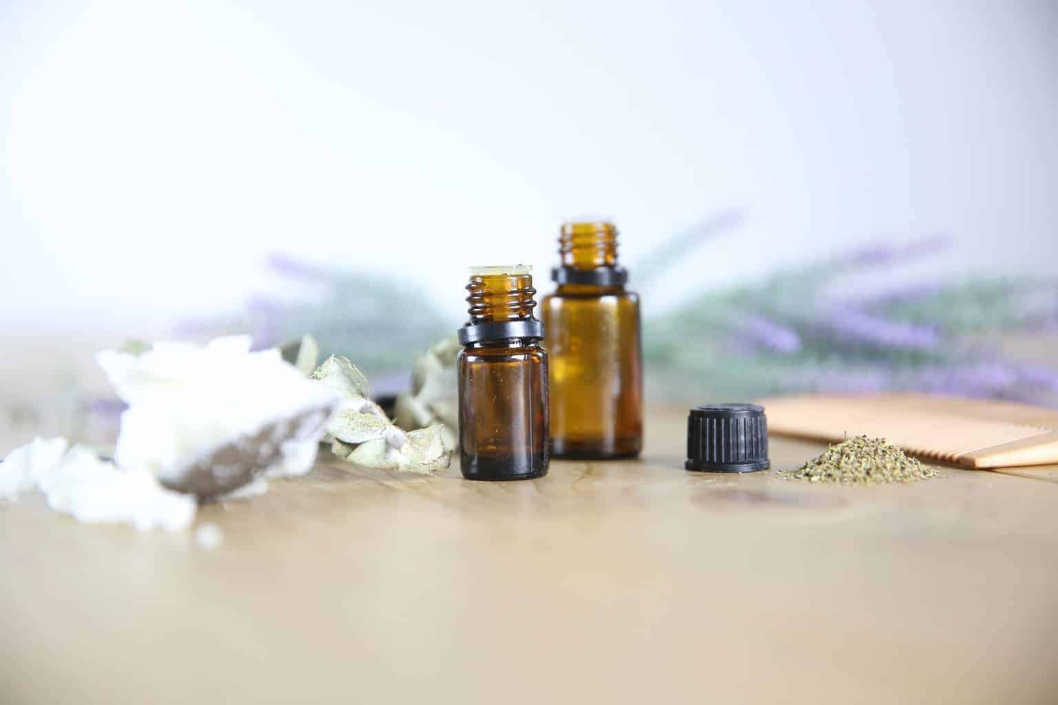 essential oil bottles with lavender sprigs on wooden table