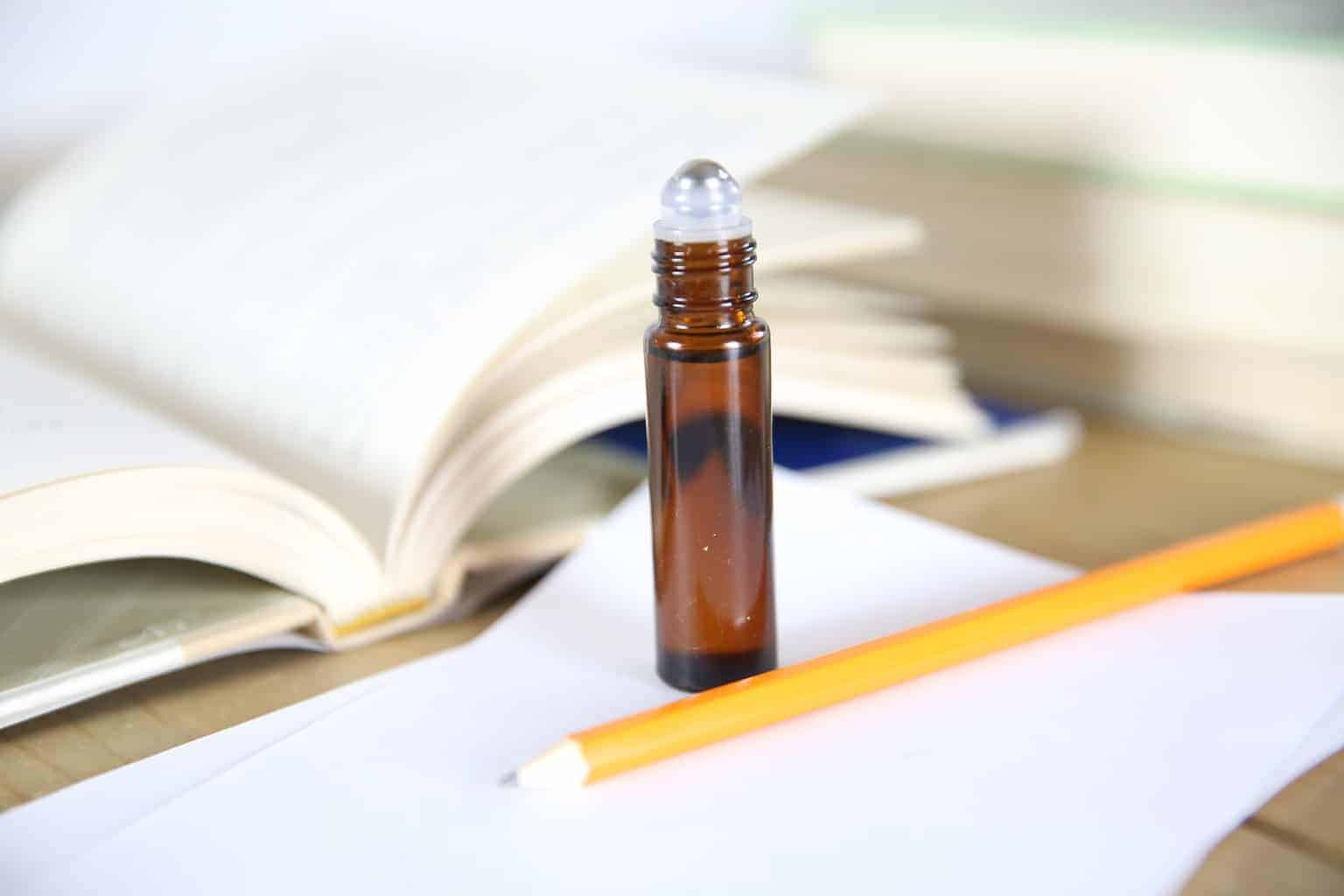 essential oil roller bottle on desk with pen and paper
