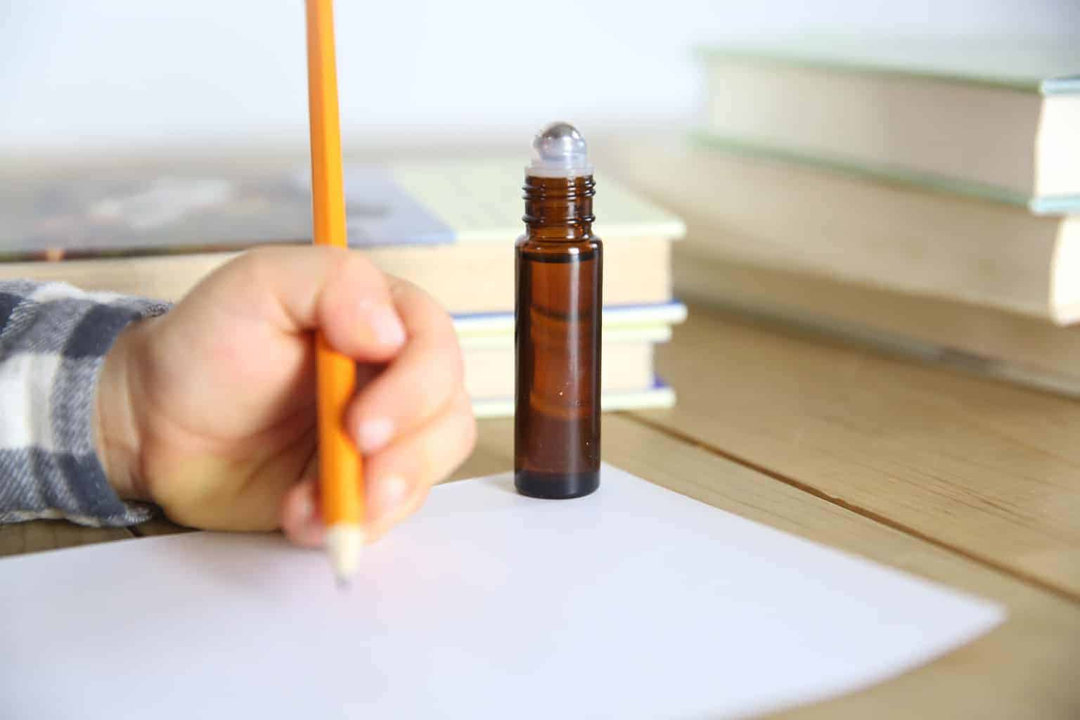 little kid studying with essential oil roller bottle for focus and concentration on table