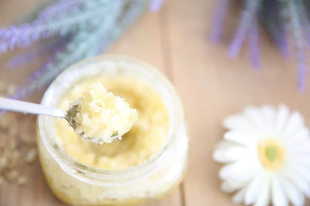 Homemade sugar scrub in a small glass container with dried lavender sprigs.