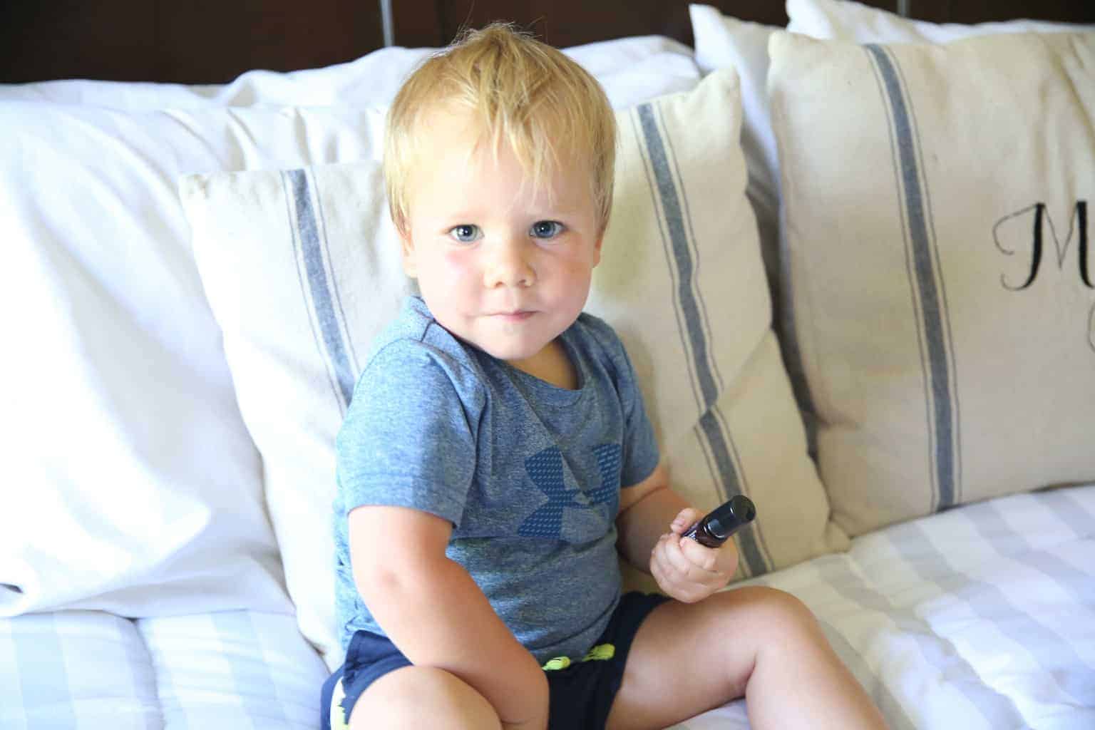 toddler sitting on bed applying tantrum tamer roller bottle