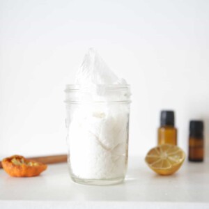 Homemade cleaning wipes in a storage mason jar on a white marble table.