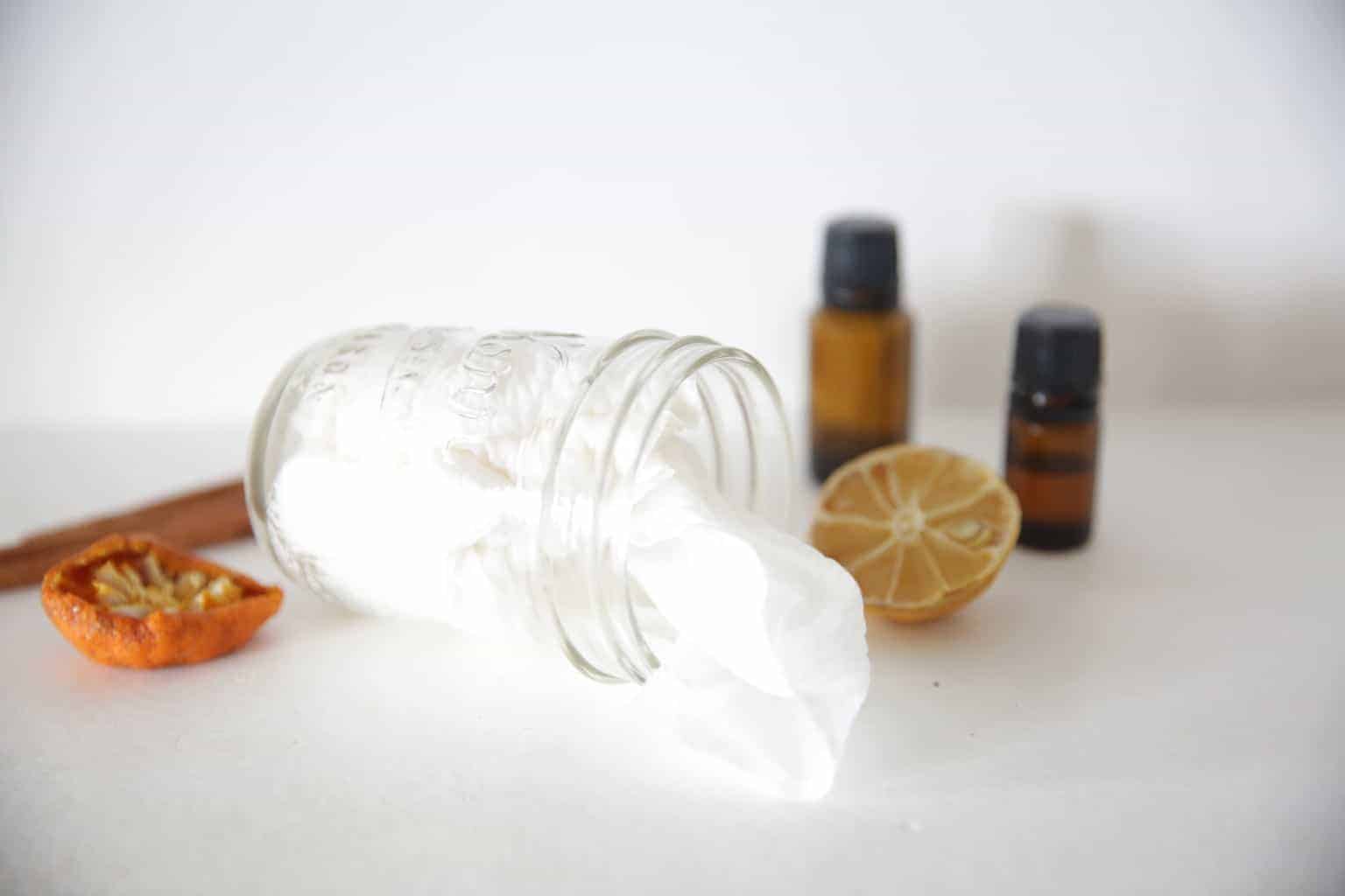 small glass jar with homemade cleaning wipes on its side with dried lemon and orange slices