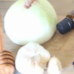 Onion and garlic on wooden table to use to relieve ear discomfort.