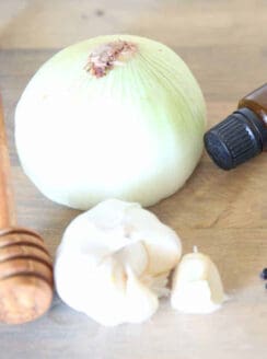 Onion and garlic on wooden table to use to relieve ear discomfort.