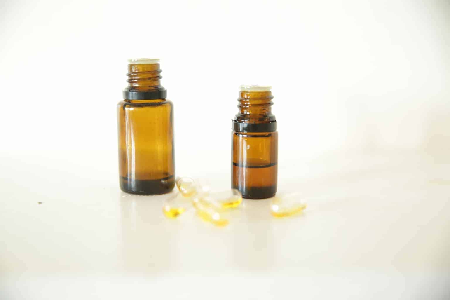 2 amber essential oil bottles with gel capsules on table