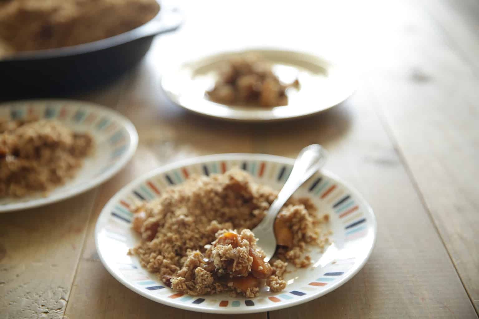 wooden table top with plates of peach crisp