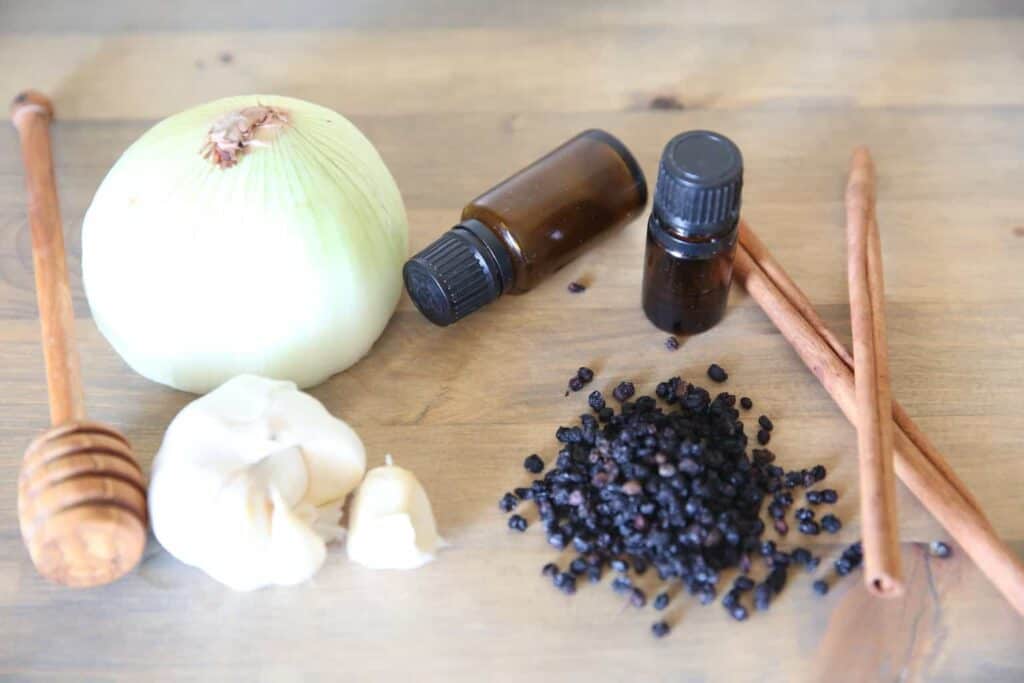 Garlic, onions and essential oils on a wooden table to make a ear discomfort roller bottle.
