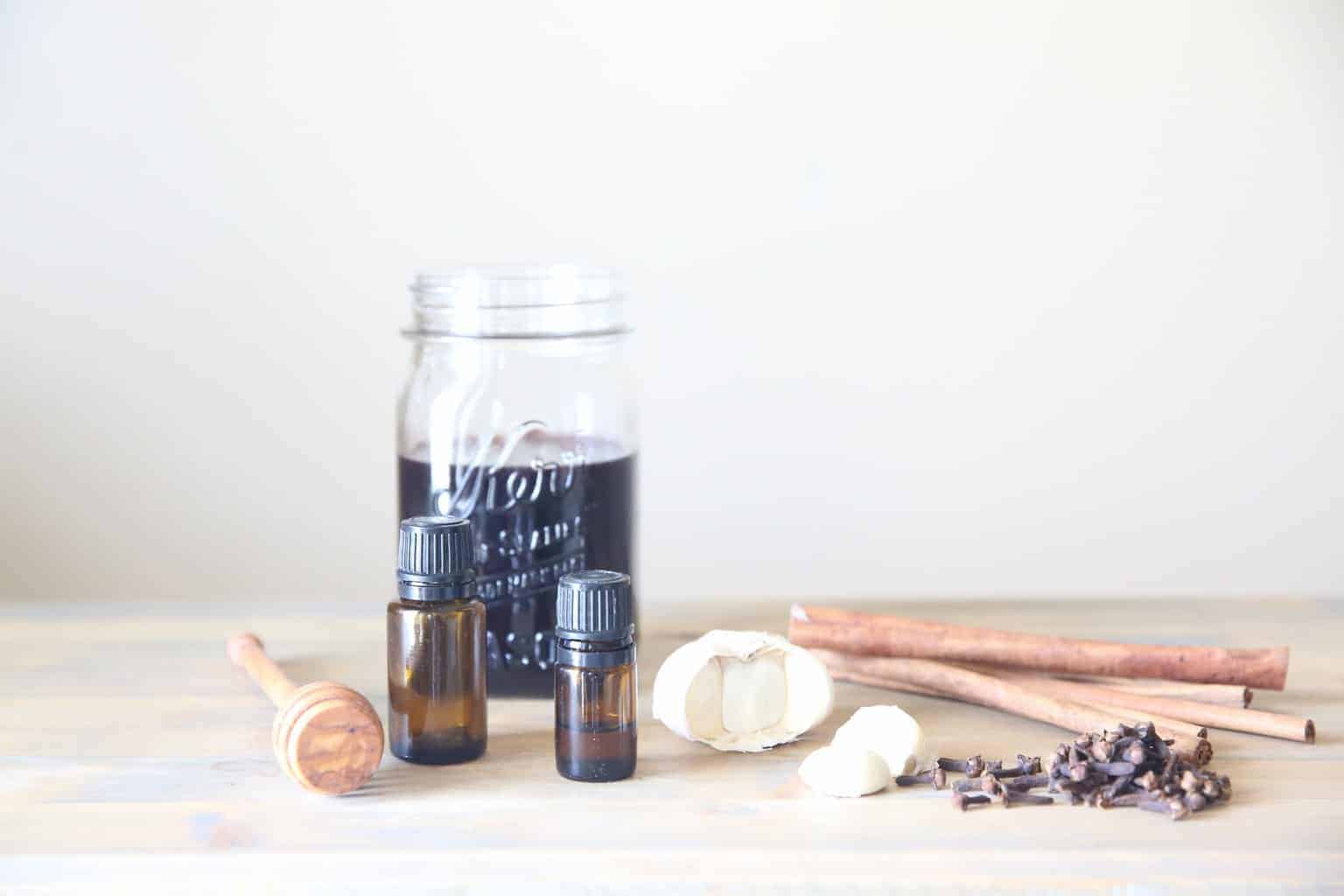 elderberry syrup with cinnamon sticks, essential oil bottles and a honey comb