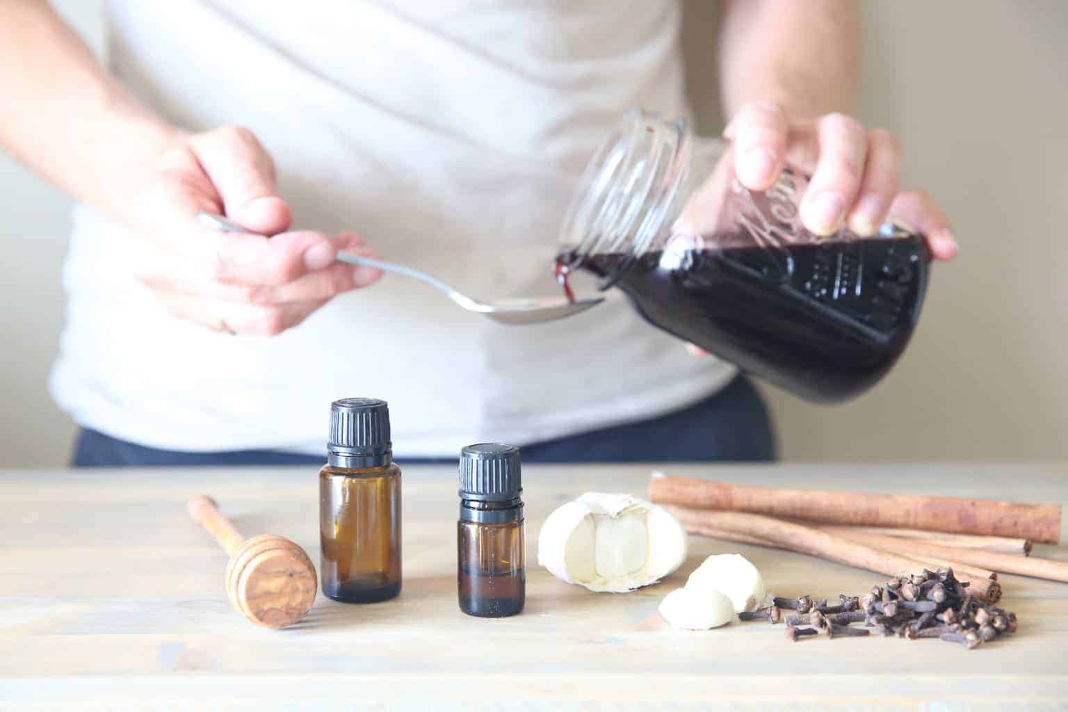 pouring elderberry syrup in a tea spoon