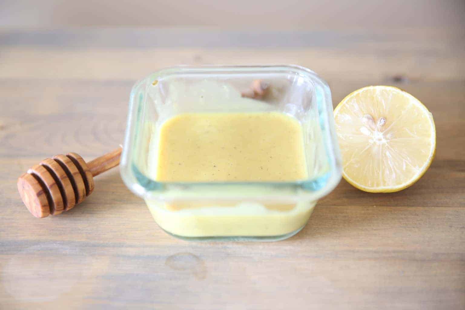 homemade honey mustard in bowl with a honey comb and lemon slice