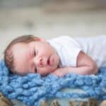 baby boy in basket with blue knit blanket