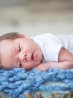 baby boy in basket with blue knit blanket
