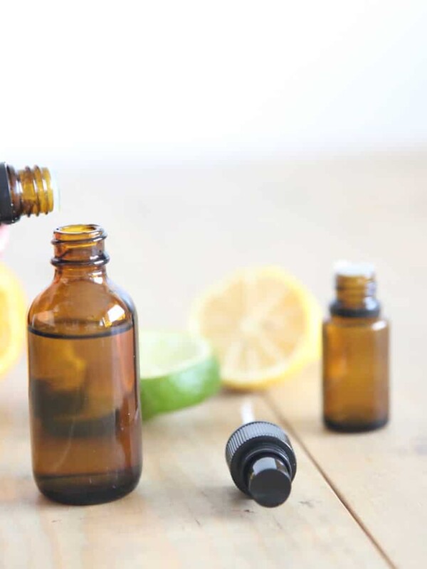 Adding essential oils to a small dropper bottle, with fresh lemons in the background.