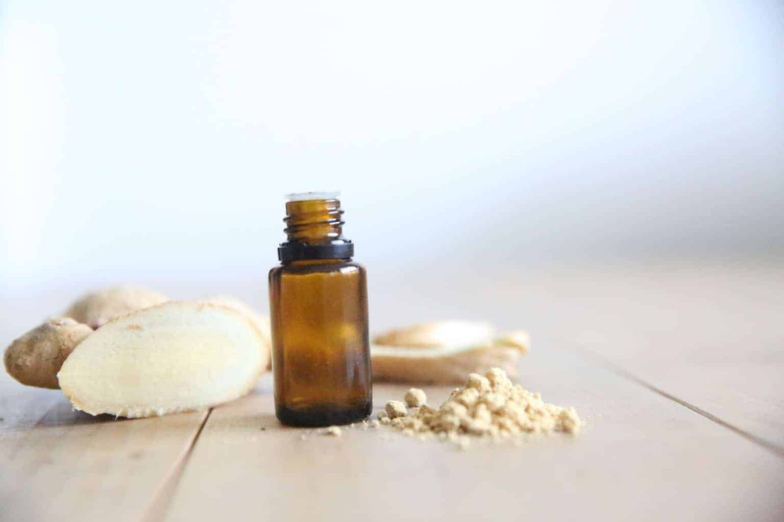 ginger root with ginger essential oil bottle on wooden table