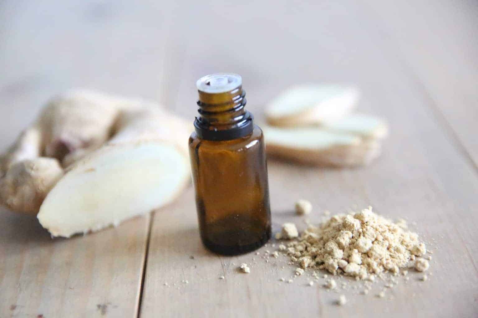 essential oil bottle with ginger on wooden table