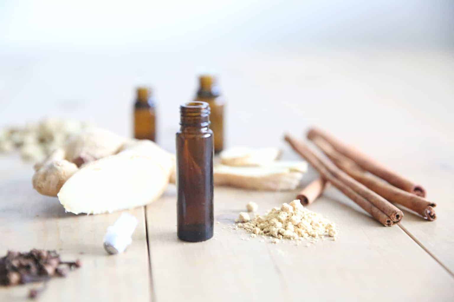 tabletop of ginger powder, root and ginger rollerball bottles.