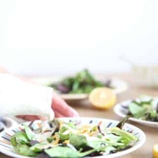 Pouring homemade healthy ranch dressing on a fresh salad.