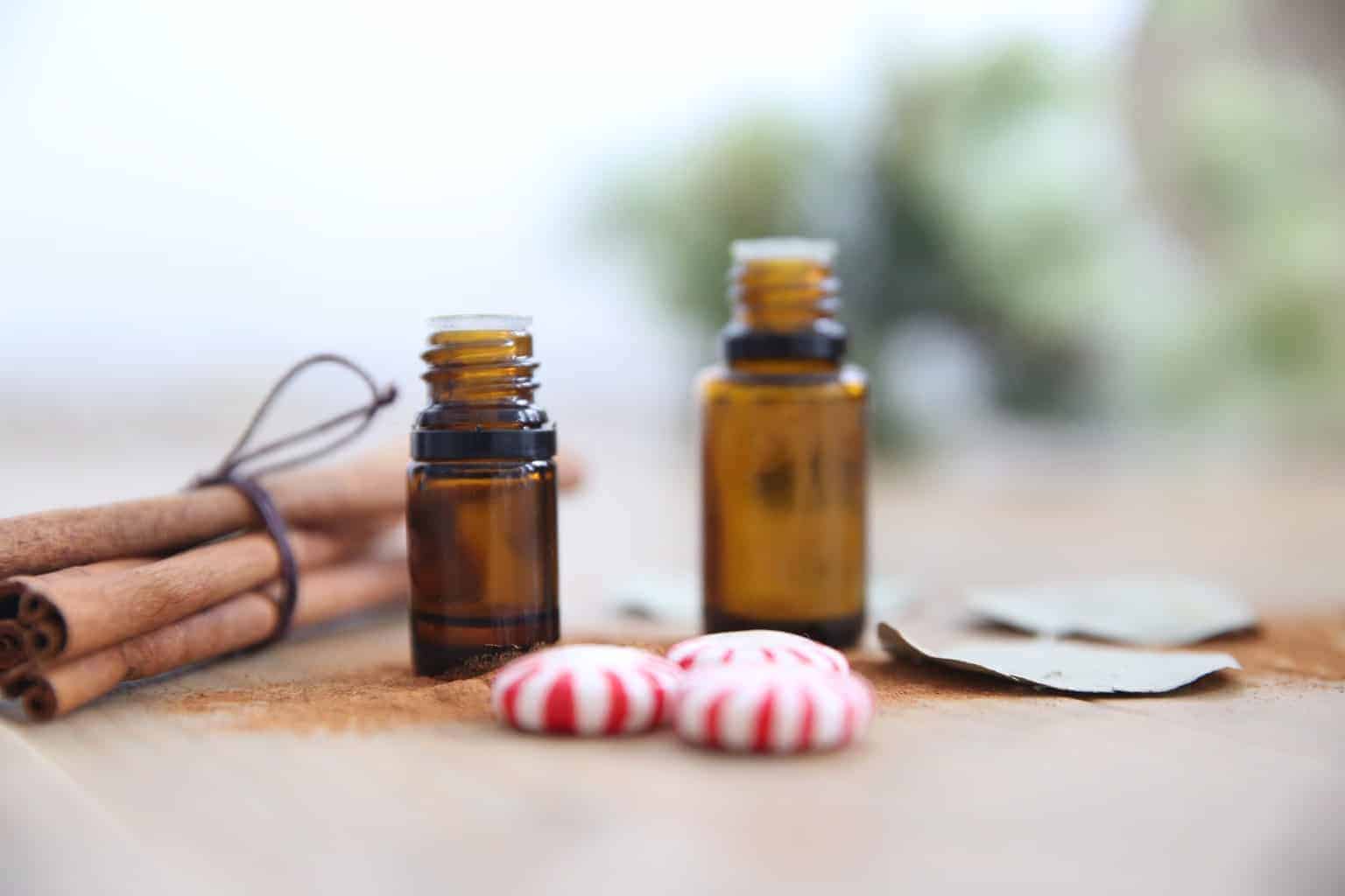 amber essential oil bottles on wood table with cinnamon sticks and eucalyptus leaves.