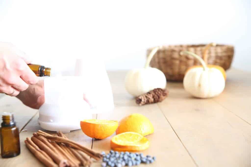 Adding fall essential oils to a white diffuser.