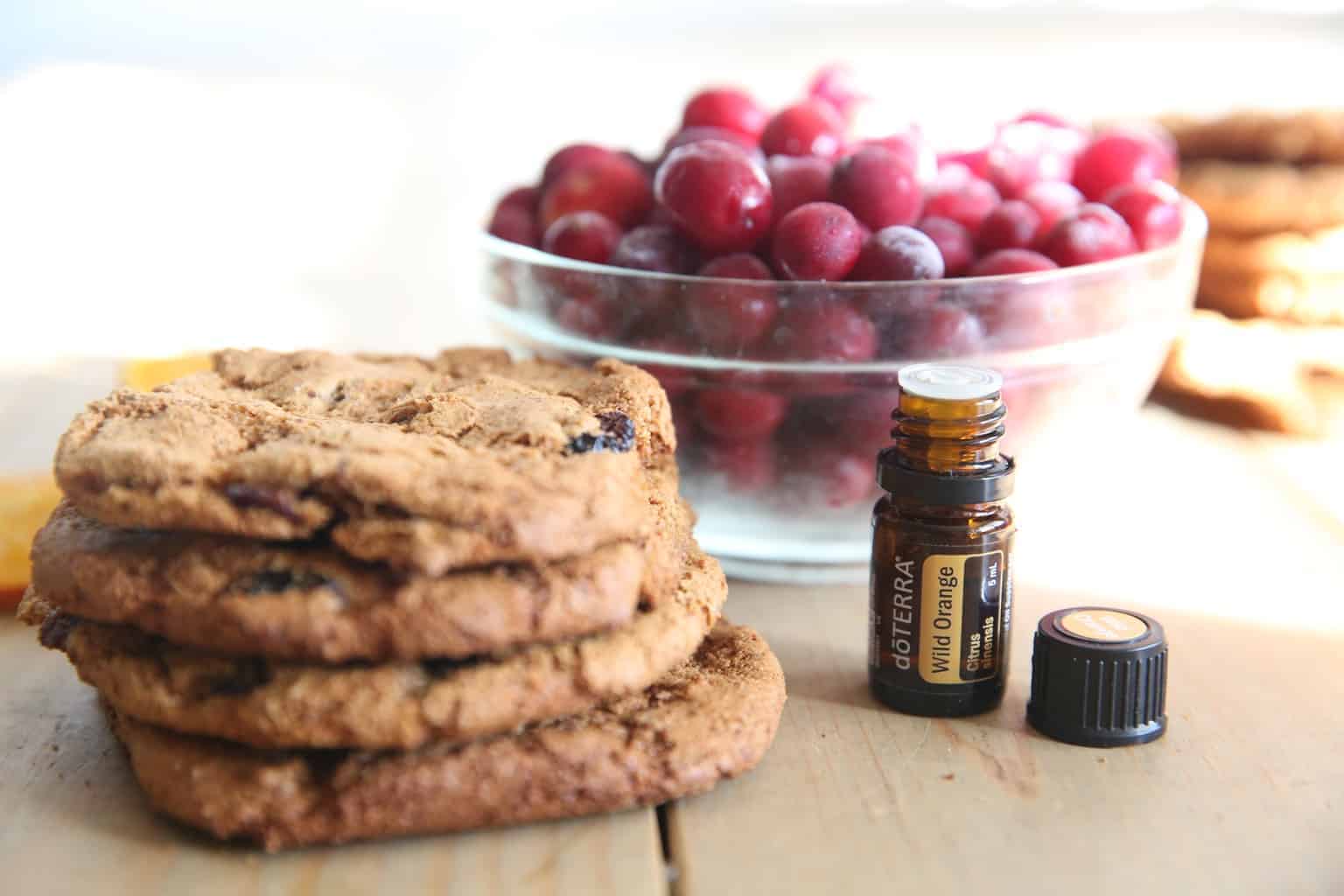 Paleo cranberry orange cookies on table with fresh cranberry in glass bowl behind them.