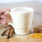 Golden milk in a coffee cup on a wooden table.