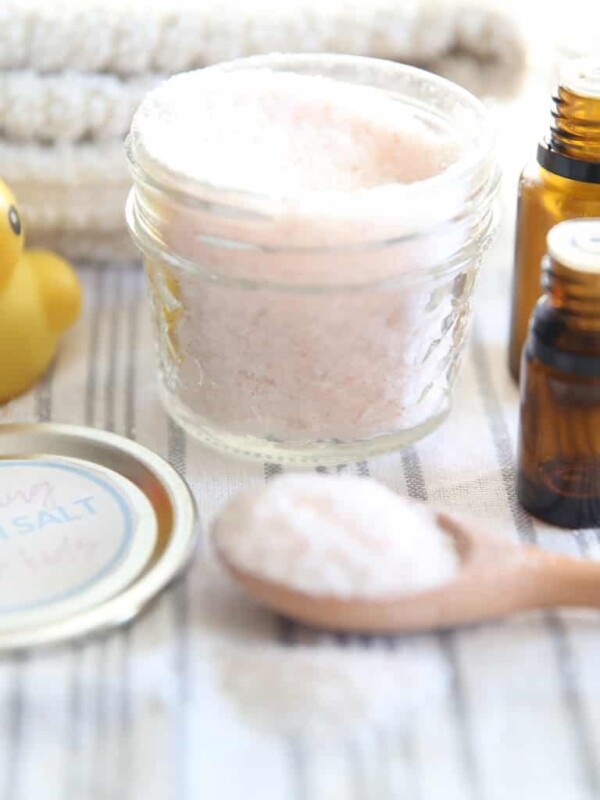 Bath salts on a blue and white striped towel with a rubber duck and a wooden spoon next to it.