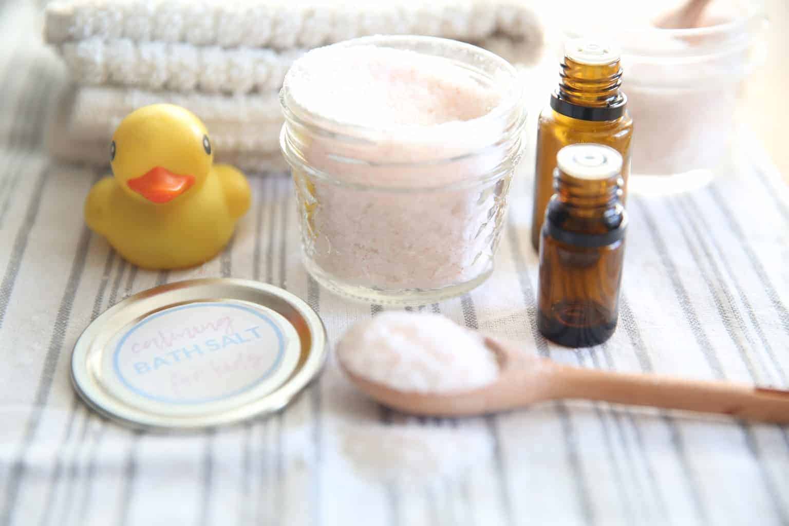 Tablespoon of homemade calming bath salts for kids next to a container of epsom salts.