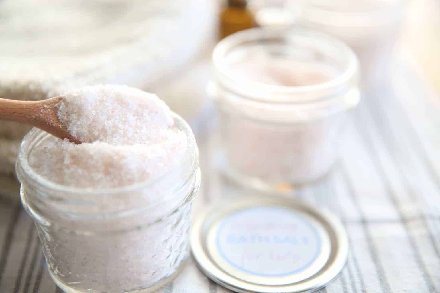Homemade bath salts with essential oils in white small mason jars.