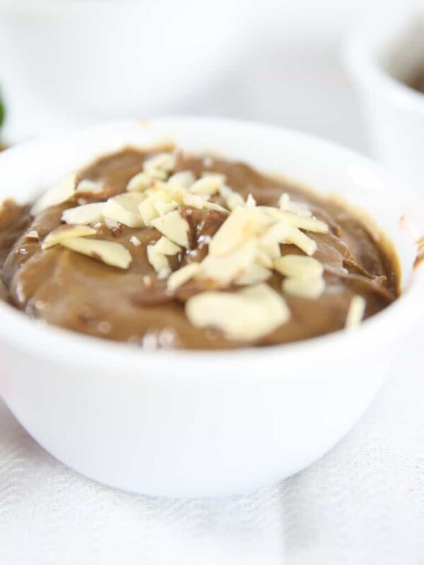 Chocolate avocado pudding with nuts on top in a small bowl.