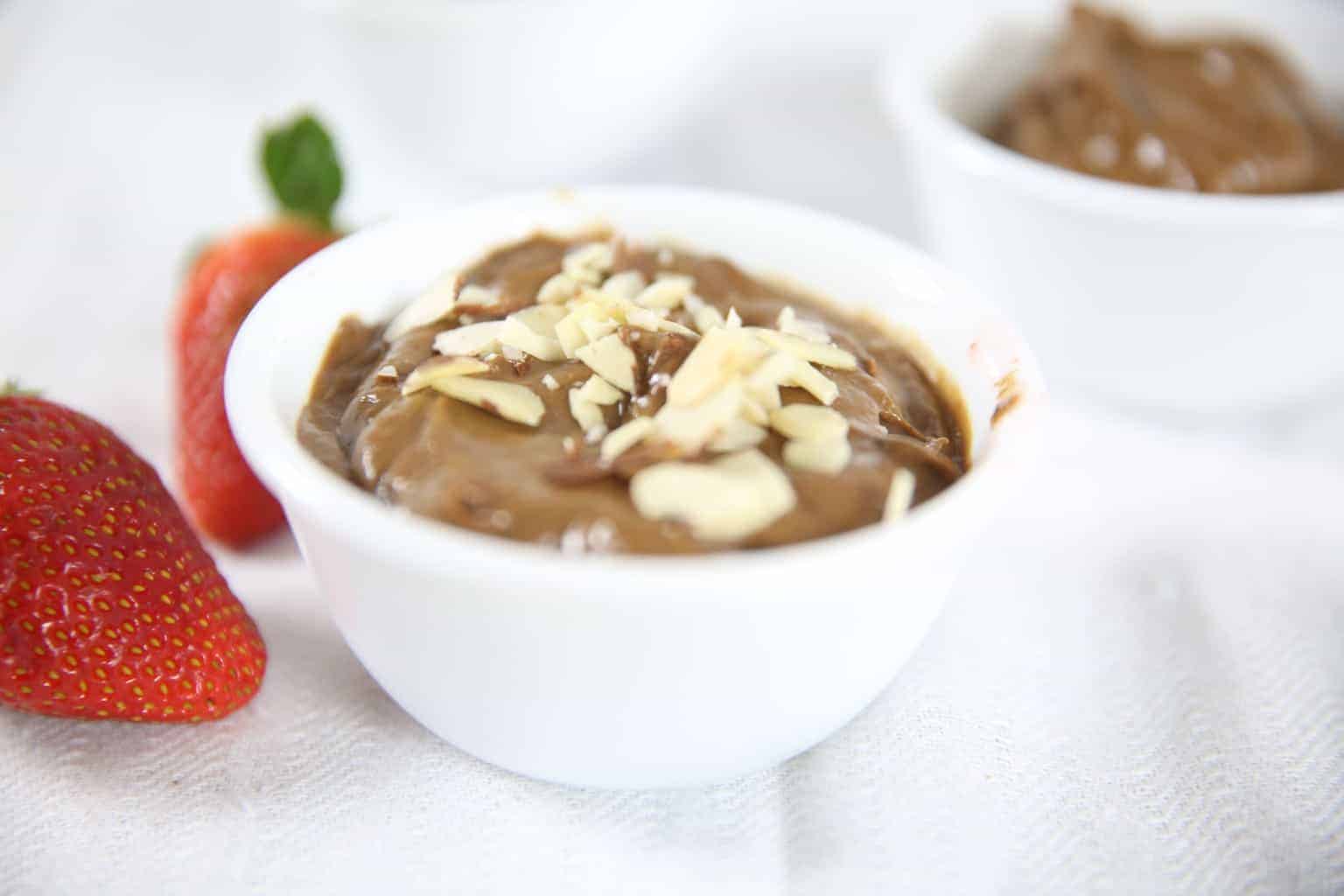 Peanut butter avocado pudding and fresh strawberries on white background.