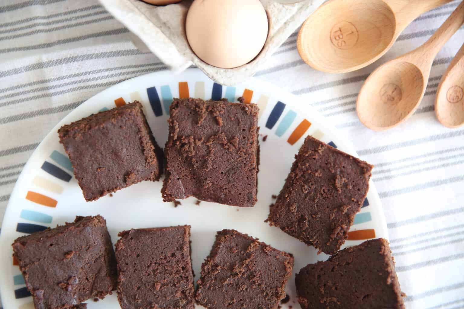 Paleo brownies on plate with wooden measuring spoons in background. 