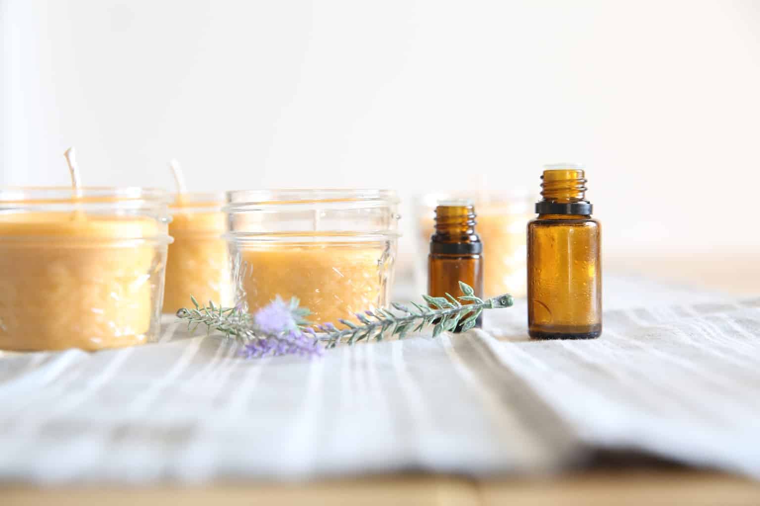 beeswax candles on table with amber essential oil bottles next to them