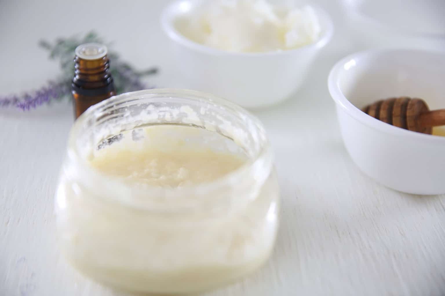 Homemade face wash with ingredients in background on white table.