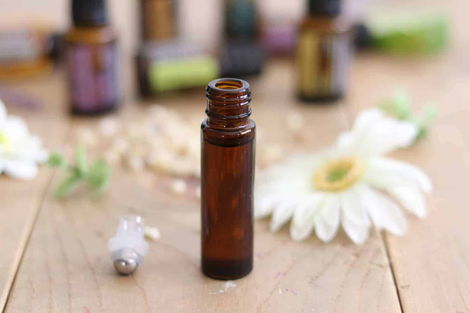 Roller bottle on table with dried flowers in background.