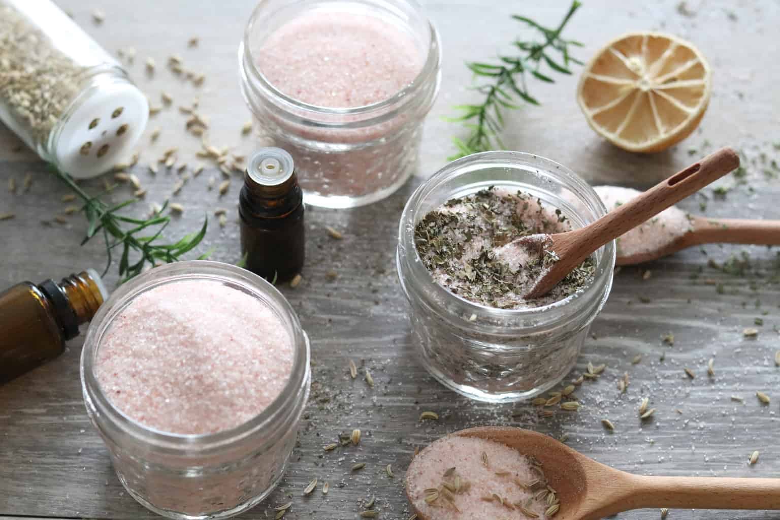 Seasonings in small mason jars with essential oil bottles on table.