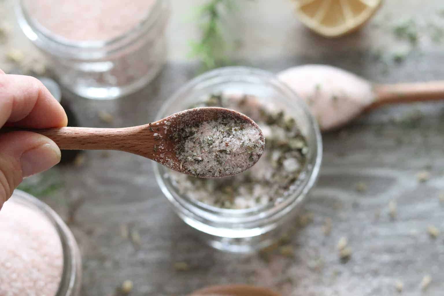 Seasoning in wooden spoon with ingredients in the background.