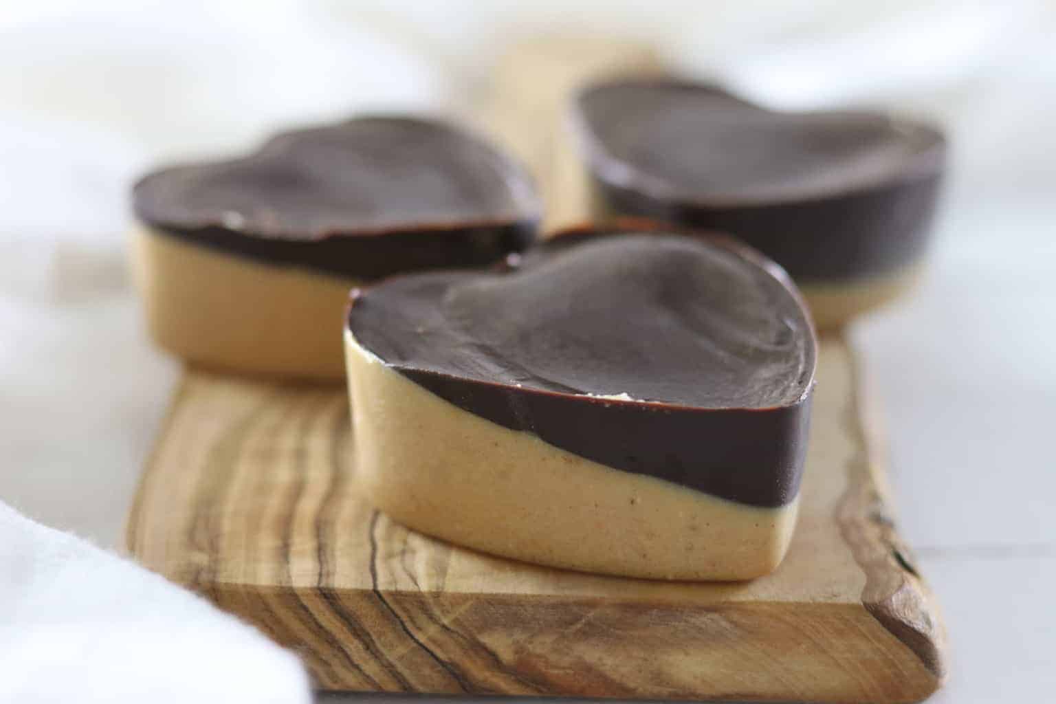 Healthy peanut butter chocolate hearts on wooden board.