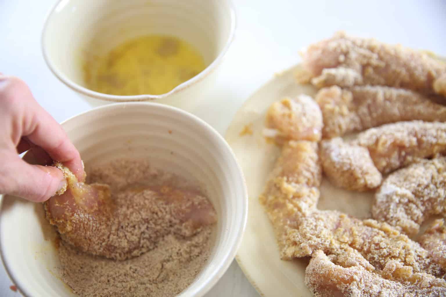 Breading chicken strip in tan bowl.