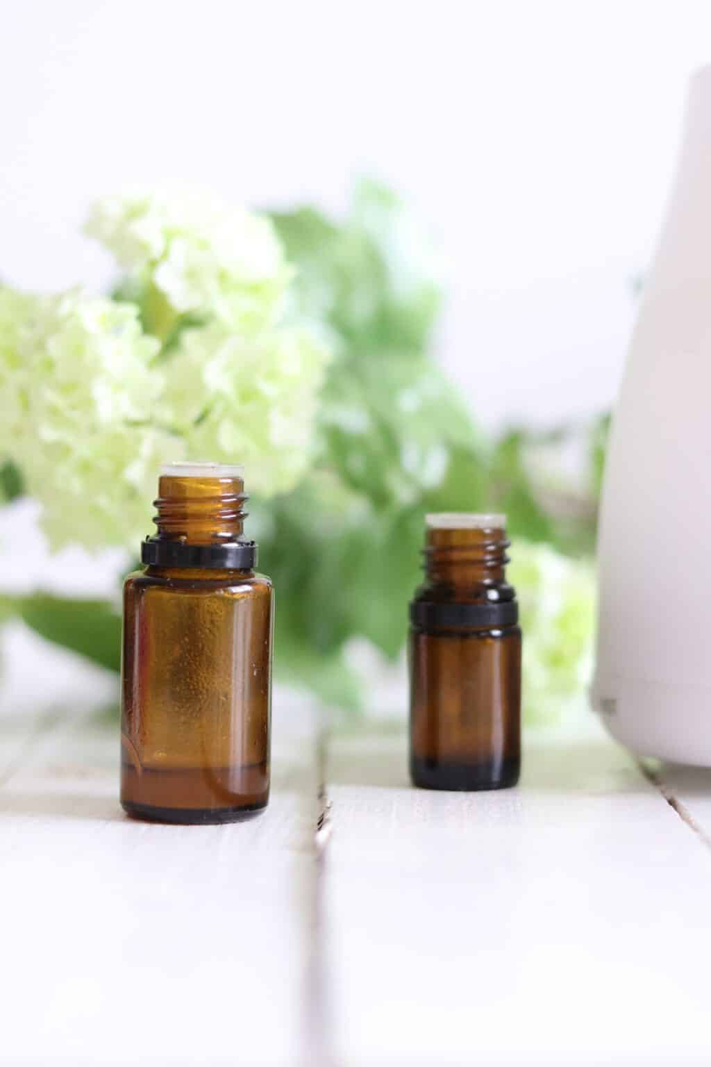 Essential oil 10ml bottles on white shiplap with flowers in background.