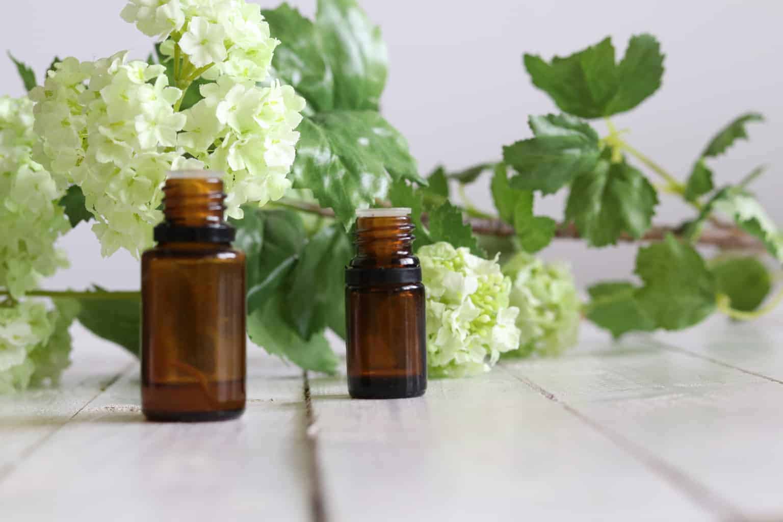 Essential oil bottles with fresh flowers in background.