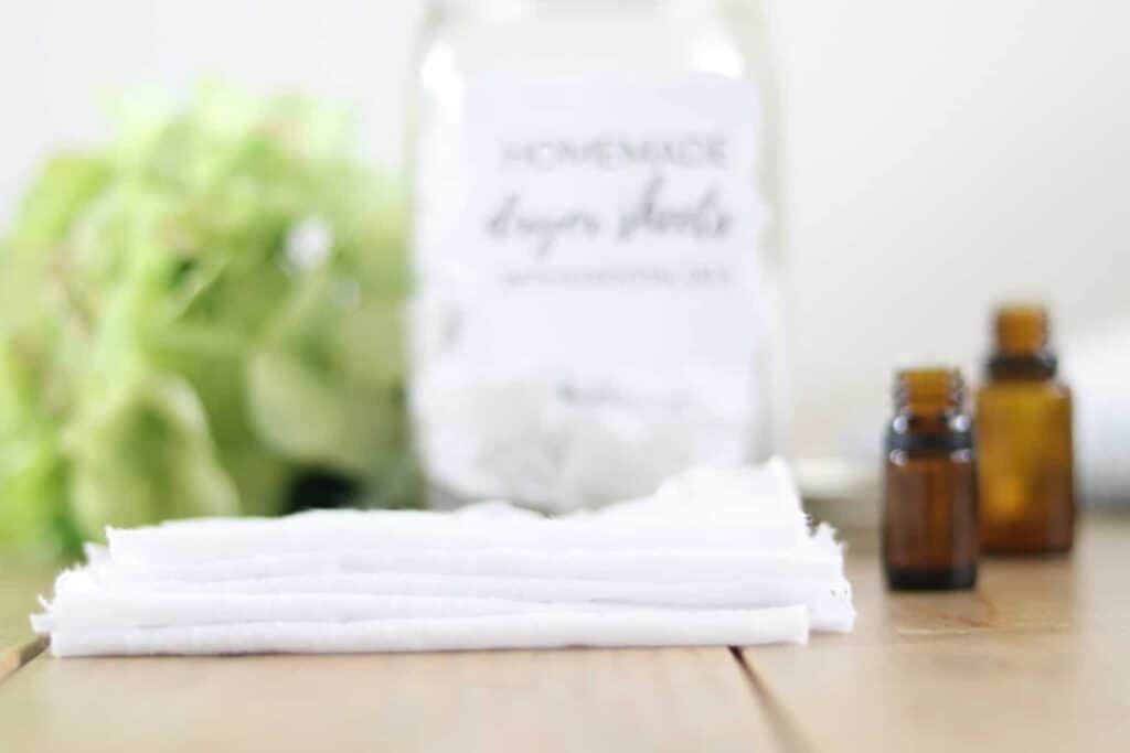 Homemade dryer sheets being made with plain sheets and essential oils on wooden working table.