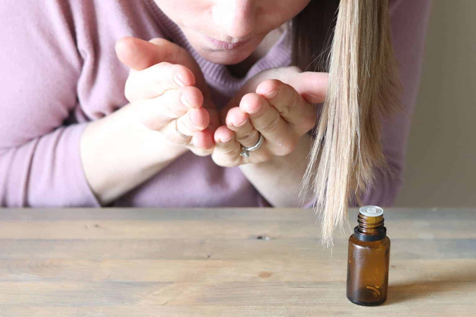 Hands cuffed over nose inhaling essential oils.