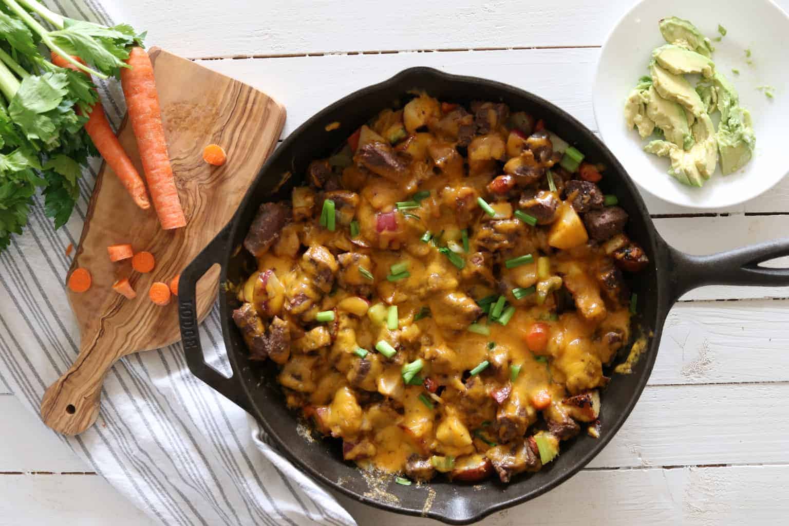 Steak melt in cast iron skillet with carrots, celery and avocados. 