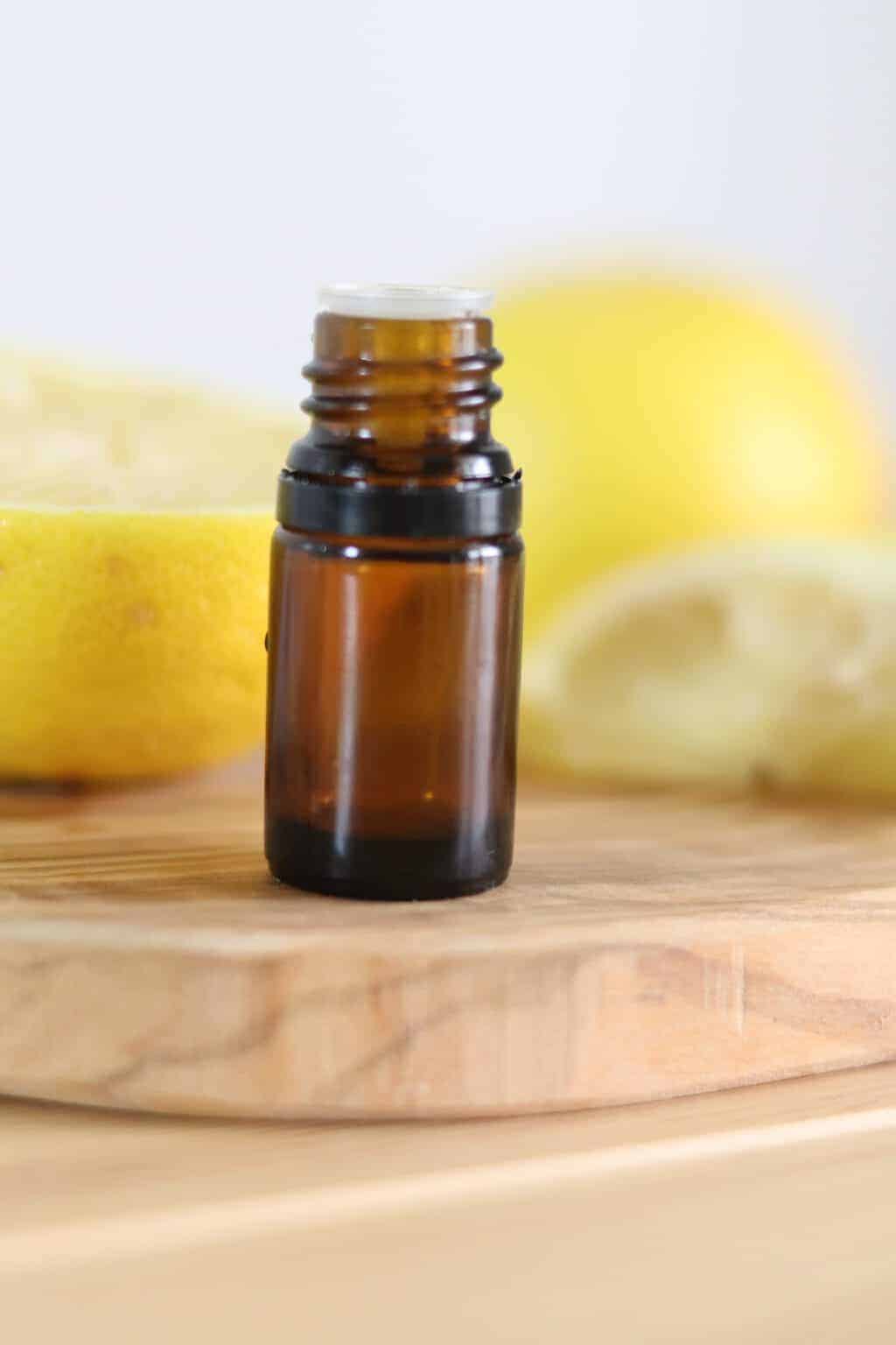Amber essential oil bottle with lemons blurred in background.