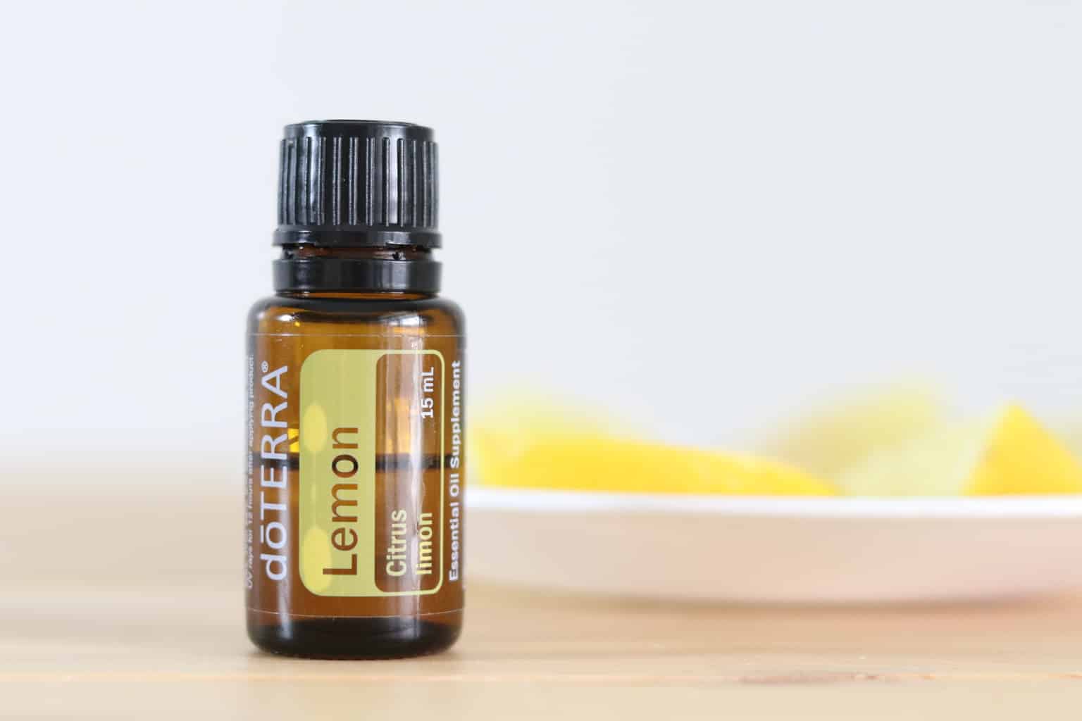 doTERRA essential oil with sliced lemons on wooden table.