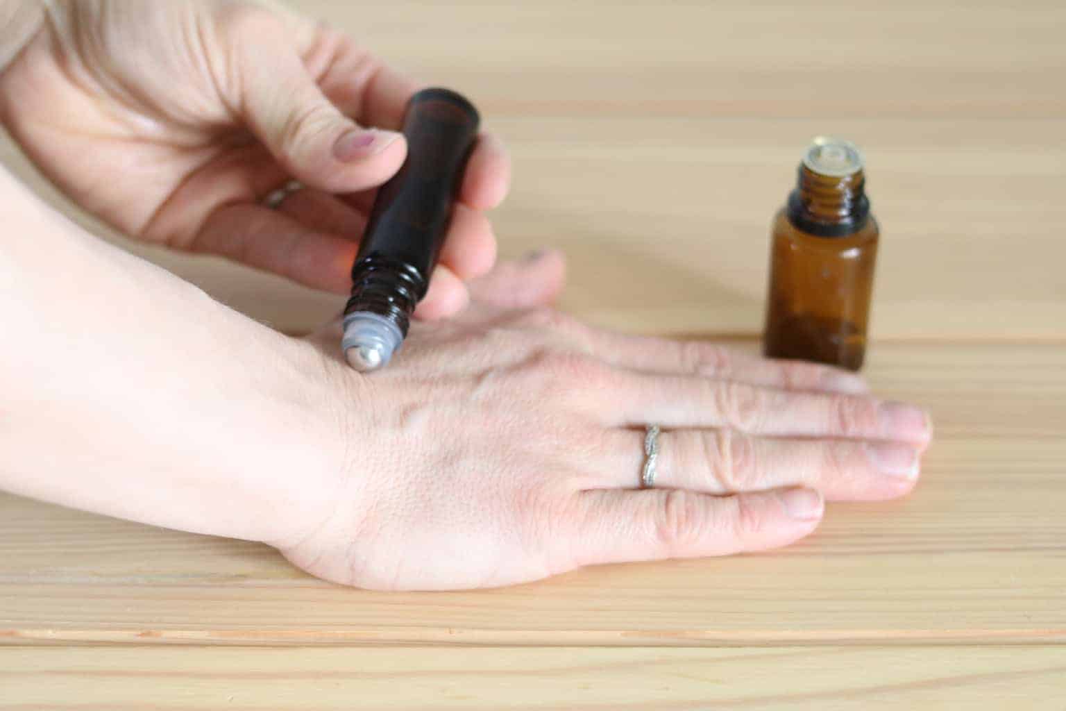 A women rubbing essential oil roller bottle on hand.