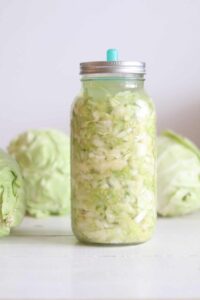 Letting the sauerkraut ferment in a tall glass jar.